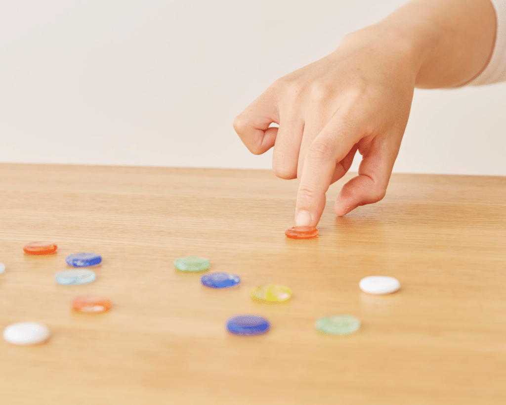 A child's hand slides a red token across a table.